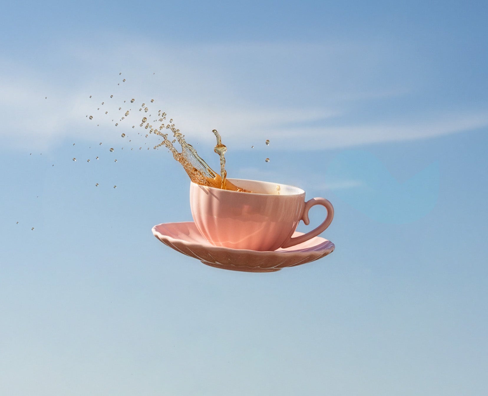 Cup of coffee with a saucer floating against a blue sky